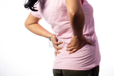 An Indian unrecognizable woman holding her back for pain showing painful expression on white background