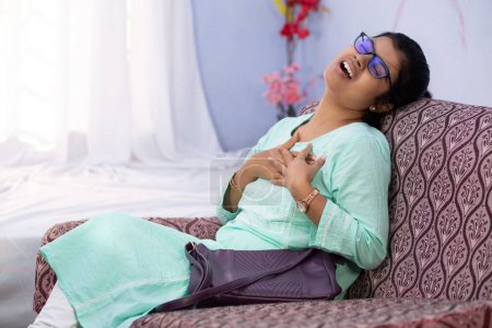 An Indian woman holding her chest for pain showing painful expression indoors