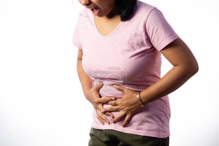 An Indian woman holding her abdomen for pain showing painful expression on white background