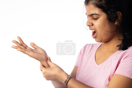Eine Inderin hält ihr Handgelenk vor Gelenkschmerzen und zeigt schmerzhaften Ausdruck auf weißem Hintergrund