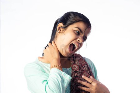 Eine Inderin hält ihren Nacken vor Schmerz und zeigt schmerzhaften Ausdruck auf weißem Hintergrund