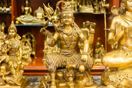 Ídolo de bronce del señor Shiva junto con otras estatuas que se venden en una tienda de mercado india
