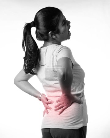 Una mujer india reteniendo su espalda por dolor mostrando expresión dolorosa sobre fondo blanco