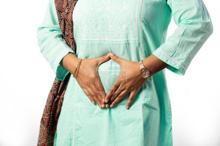Una mujer india mostrando su vientre como útero sano sobre fondo blanco