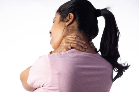 Una mujer india sosteniendo su cuello por dolor mostrando expresión dolorosa sobre fondo blanco
