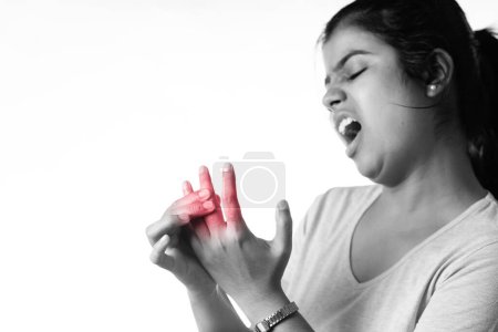Una mujer india sosteniendo sus dedos por dolor en las articulaciones mostrando expresión dolorosa sobre fondo blanco