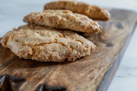 A variety of freshly baked, homemade Spanish perrunillas cookies and crackers on a wooden board against a marble background- the perfect snack for healthy eating and well being.