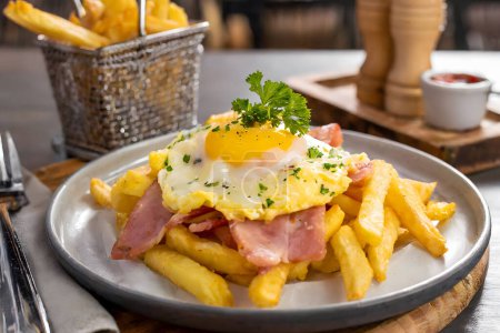 A delicious plate of crispy fries topped with a sunny-side-up egg, served for breakfast.
