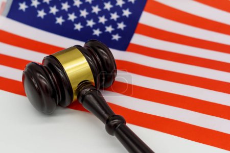 Foto de Justice Under the Stars and Stripes. Un mazo de jueces descansa en un bloque de sonido contra el telón de fondo de una bandera estadounidense, simbolizando la ley y el orden en los Estados Unidos. - Imagen libre de derechos