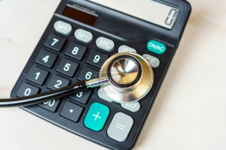 Stethoskop und Taschenrechner auf dem Tisch. Arztkosten, Gesundheitskosten, finanzielle Belastung durch Krankheit