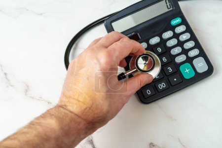 Photo for Financial Health Checkup. A stethoscope and calculator represent the financial health of a business or individual. - Royalty Free Image