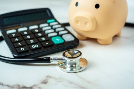 A piggy bank with a calculator and stethoscope showcases the financial aspect of healthcare.