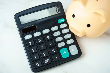 Calculator and piggy bank hint at financial planning and saving strategy.
