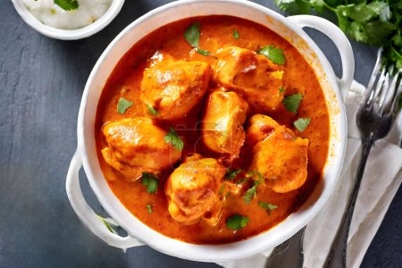 The image showcases a delicious serving of Chicken Tikka Masala, garnished with herbs, making it visually appealing and indicative of rich flavors.