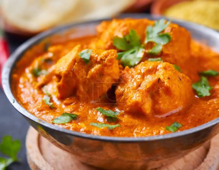 The image showcases a delicious serving of Chicken Tikka Masala, garnished with herbs, making it visually appealing and indicative of rich flavors.