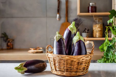 Beautiful eggplants with vibrant purple skin in a rustic wicker basket, placed on a kitchen counter with soft lighting