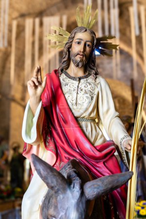 Téléchargez les photos : Une statue de Jésus chevauchant un âne. La statue est celle d'un homme avec une barbe et une couronne sur la tête - en image libre de droit
