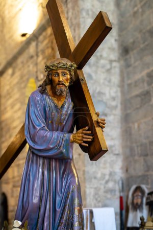 Jesusstatue mit einem Holzkreuz. Die Statue besteht aus Holz in einem Prozessionsschritt der Heiligen Woche.