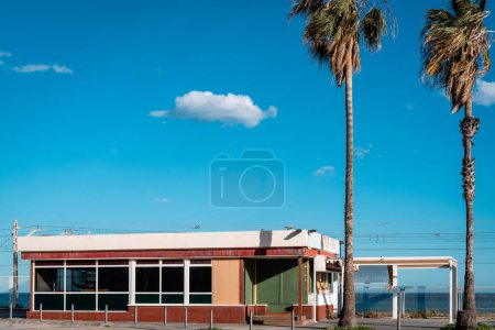 Photo for Single-Story Commercial Building, Diner, with Palm Trees under Clear Blue Sky - Royalty Free Image