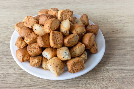 Kuciukai - galletas tradicionales lituanas de Navidad con semillas de amapola o patatas fritas en un plato sobre una superficie de mesa de roble