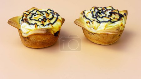 Foto de Vista lateral de dos pasteles, cupcakes con requesón y chocolate sobre fondo naranja - Imagen libre de derechos