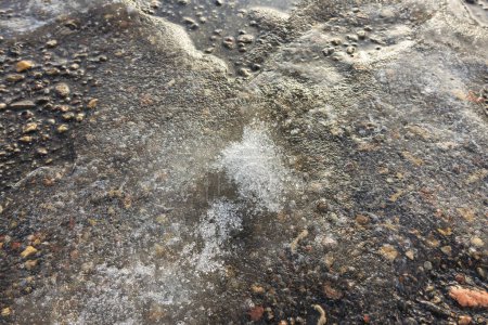 Photo for Close-up view of asphalt covered with melting snow and ice shining in the sun on a calm spring day - Royalty Free Image