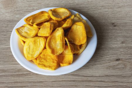 Keripik Sukun oder Brotfruchtchips sind Lebensmittel aus Brotfrüchten, die in dünne Scheiben geschnitten und dann gebraten werden, bis sie trocken und knusprig sind. Serviert auf weißem Teller