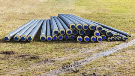A pile of water pipes with thermal insulation isotherm in a meadow on a sunny day in spring
