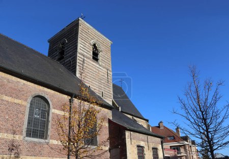 Foto de Vista de la histórica iglesia parroquial de Nuestra Señora en Nieuwerkerken cerca de Aalst en Flandes Oriental, Bélgica. Día soleado de otoño con cielo despejado, y espacio de copia arriba a la derecha. - Imagen libre de derechos