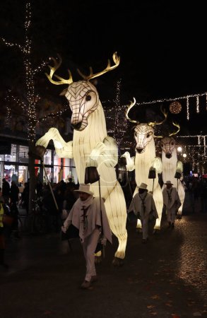 Foto de AALST, BÉLGICA 2 DICIEMBRE 2022: Figuras gigantes iluminadas entretienen a multitudes en la calle principal de compras en el festival de Navidad de Aalst Twinkles. La noche marca el comienzo del período de vacaciones en Flandes Oriental. - Imagen libre de derechos