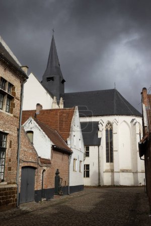 Foto de View of Diest Beguinage and St. Catherines Church, in Flemish Brabant in Belgium, against a dramatic background of dark stormy sky. Unesco world heritage site. - Imagen libre de derechos