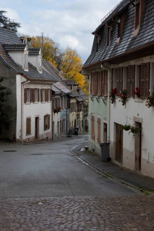 Photo for View of a typical quaint backstreet with historic buildings, in the town of Thann, in the Alsace area of Grand-est in France. Urban scene in Autumn, copy space below. - Royalty Free Image