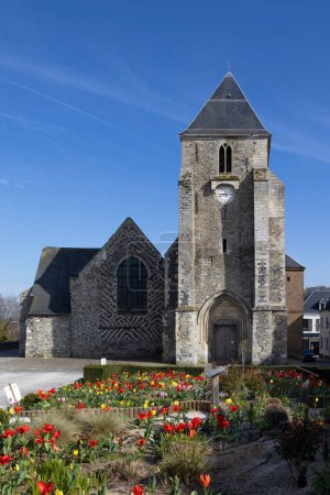 Photo for The medieval church of St. Martins in  Saint-Valery-sur-Somme, France, on a sunny spring evening with tulips in the forground. Somme department of Hauts-de-France - Royalty Free Image