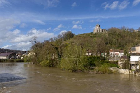 View of a swollen River Meuse at Dun-sur-Meuse, in the Meuse Valley in France. The church of Our Lady is visible in it's prominent hill top location.
