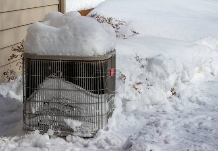 Photo for Close up view of an exterior home air conditioning unit, covered with deep snow following a winter blizzard - Royalty Free Image