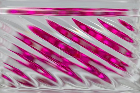 Foto de Fondo de textura abstracta desenfocada con una vista macro de una hermosa superficie de cristal moderno con líneas diagonales, que refleja el color rosa rosado con bokeh - Imagen libre de derechos