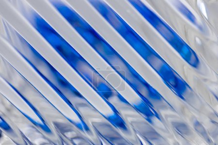 Téléchargez les photos : Fond de texture abstrait déconcentré avec une vue macro d'une belle surface en cristal moderne avec des lignes diagonales, réfléchissant la couleur bleue avec bokeh - en image libre de droit