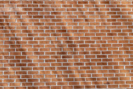 Photo for Close up texture background of a modern traditional exterior red clay brick wall in running bond (stretcher bond) pattern, with diagonal shadows cast from angled sunlight - Royalty Free Image