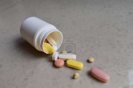 Pills scattered from white bottle in different sizes