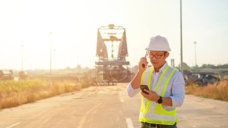 Photo for Engineer talking on walkie-talkie and using smart phone for working at construction site - Royalty Free Image