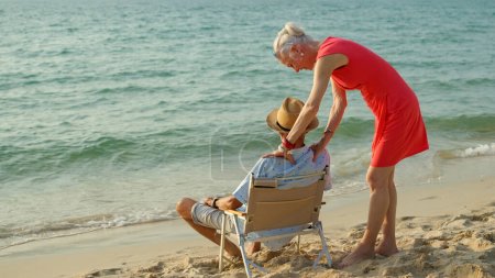 Foto de Una pareja de ancianos abraza sus hombros en la playa en sus vacaciones de verano y sonríen y disfrutan de sus vacaciones. - Imagen libre de derechos