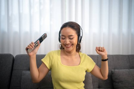 Téléchargez les photos : Femme portant des écouteurs et écoutant de la musique et chantant heureux à la maison en vacances. - en image libre de droit