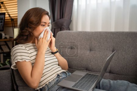 Foto de Mujer asiática está enferma y hablando con el médico a través de una videollamada sobre la enfermedad y la medicina en el ordenador portátil en casa. - Imagen libre de derechos