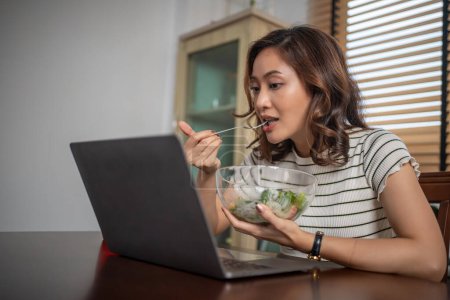 Photo for Woman eating healthy salad and working at home - Royalty Free Image