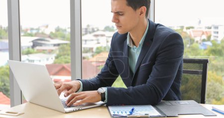 Photo for Businessman using laptop and contemplating while working at his desk in the office. - Royalty Free Image