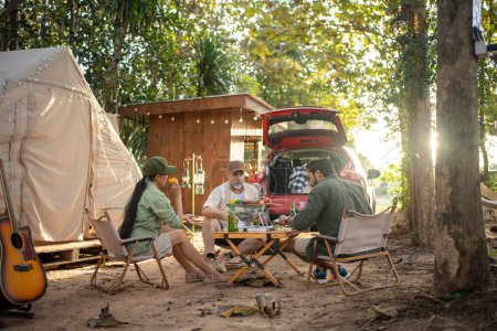 Foto de Group tourists drinking beer-alcohol and play guitar together with enjoy and happiness in Summer while camping - Imagen libre de derechos