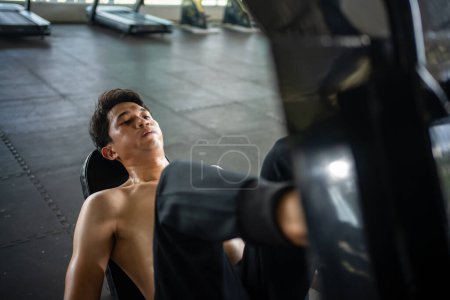 Photo for Asian men athletes doing leg press exercises with machines to strengthen muscles for health care at the gym stadium - Royalty Free Image