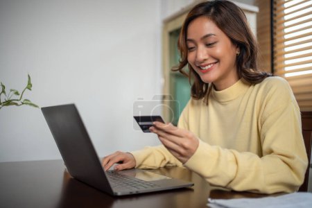 Foto de Las mujeres que utilizan el teléfono inteligente y el ordenador portátil para ir de compras en línea y el pago con tarjeta de crédito en casa - Imagen libre de derechos