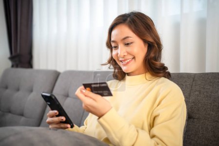 Téléchargez les photos : Femmes utilisant le téléphone intelligent et ordinateur portable pour faire des achats en ligne et le paiement par carte de crédit à la maison - en image libre de droit