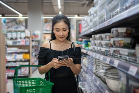 Foto de Mujer joven dentro de una tienda mirando un producto y leyendo la etiqueta. Persona que elige verduras y frutas y compras en el supermercado - Imagen libre de derechos